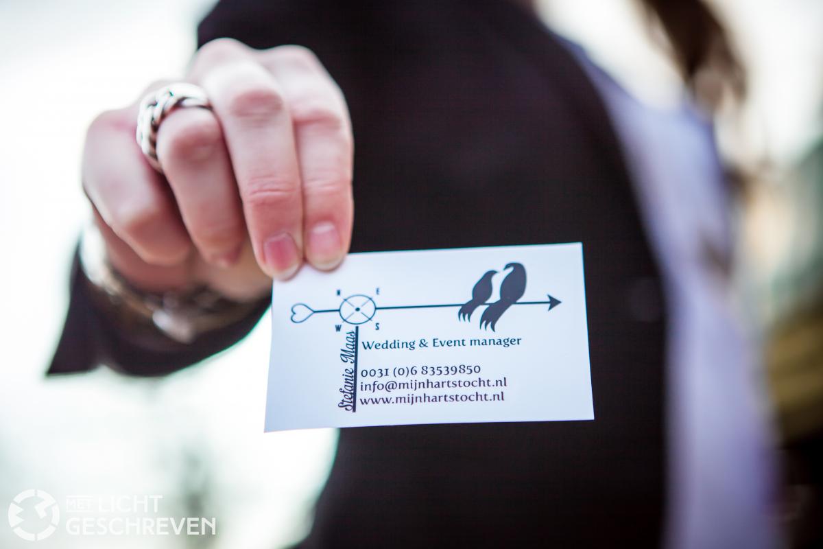 Hand met visitekaartje van wedding planner Hartstocht.