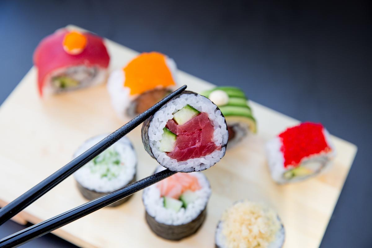 Sushi wordt met eetstokjes van plankje opgepakt