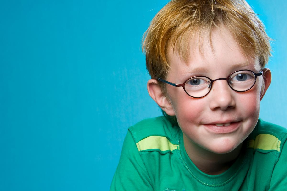 Jongen met oranje haren en bril bij met een lichtblauwe achtergrond