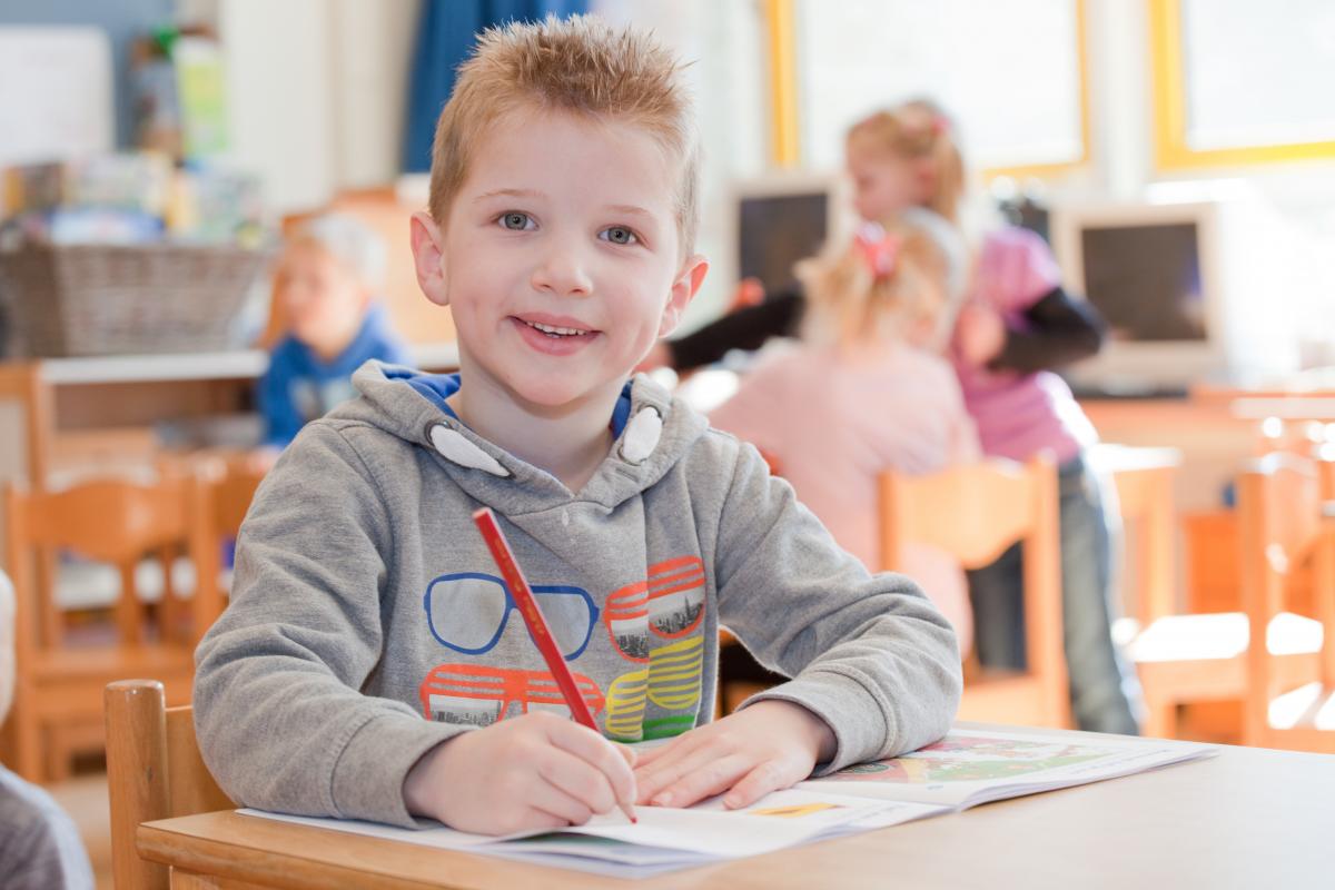 Jongen uit groep 3 werkt in zijn werkboek 