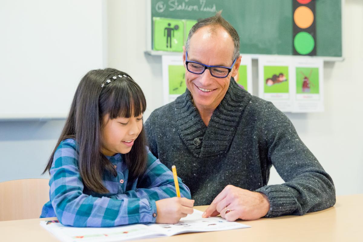 Leeraar en leerling werken samen in een werkboek in de klas.