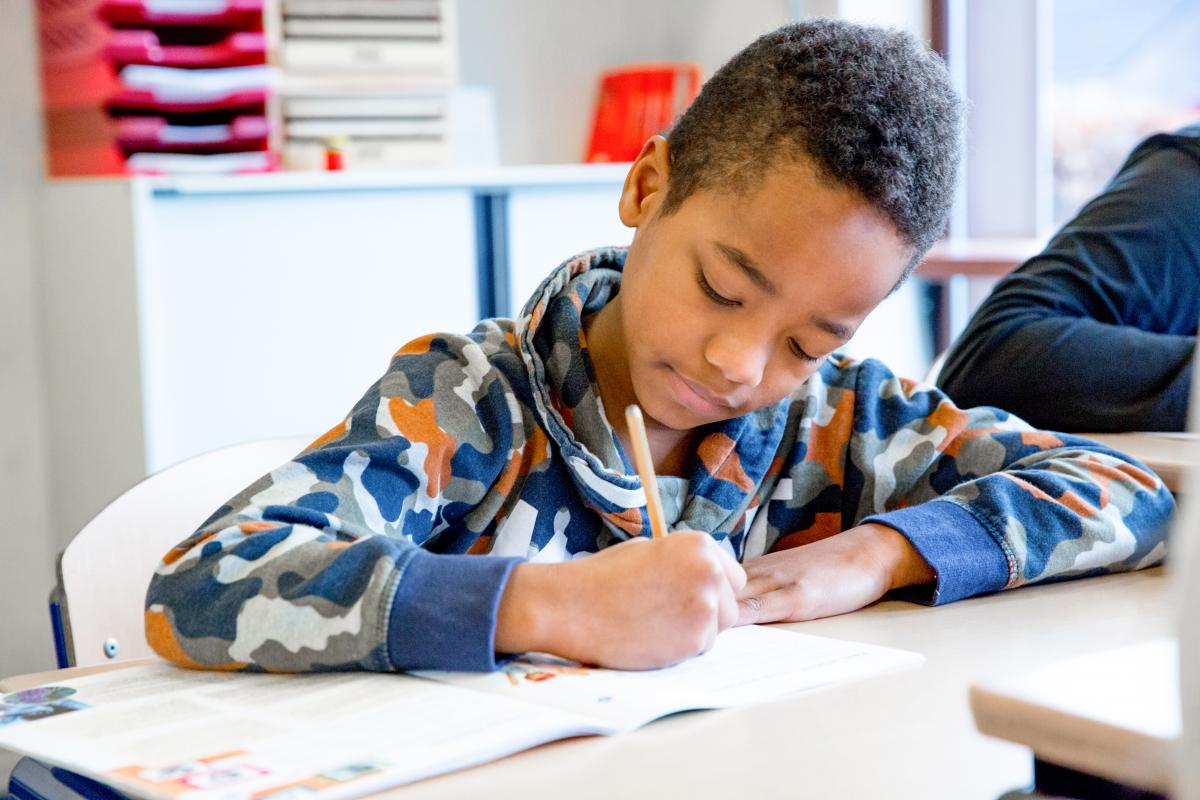 Jongen werkt zelfstandig in zijn werkboek.