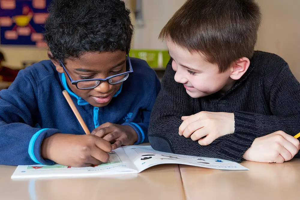 Redactionele fotografie van kinderen op school bezig met lesmateriaal voor educatieve uitgever